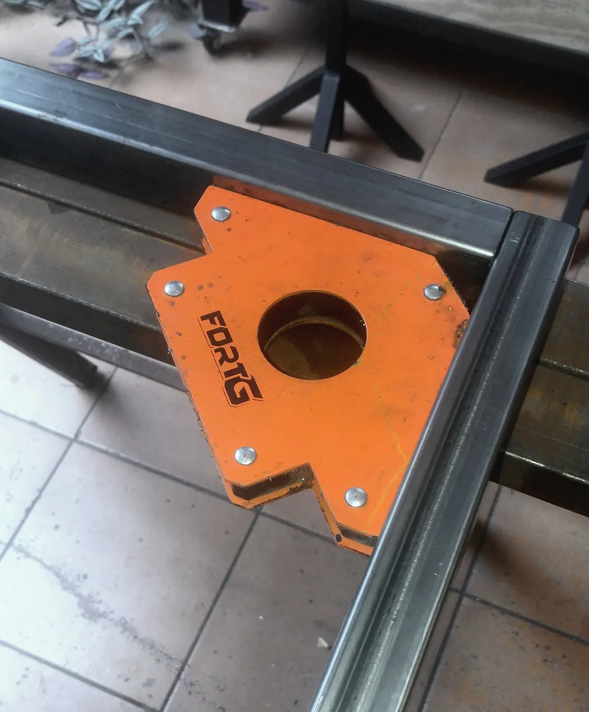 Steel tubes held at a right angle by an orange welding magnet